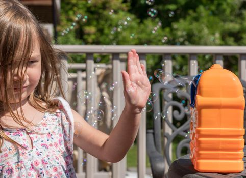 Childrens toy soap bubble blower with young girl watching the bubbles being blown