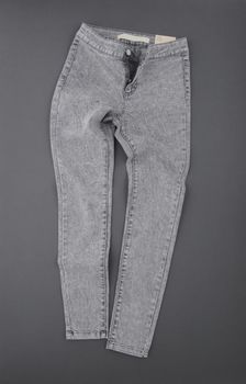 fashionable denim pants on grey background, top view