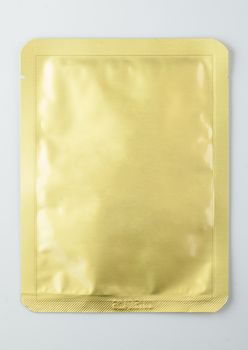 gold sealed cosmetic sachet, isolated on white background