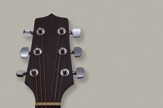 Close up of an acoustic guitar headstock on grey background.