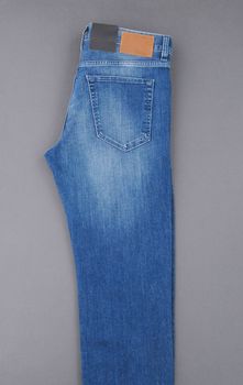 fashionable denim pants on grey background, top view