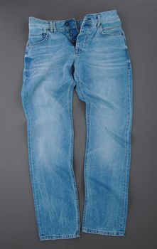 fashionable denim pants on grey background, top view