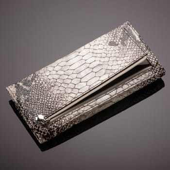 Fashionable women's wallet made of crocodile skin on a brown background