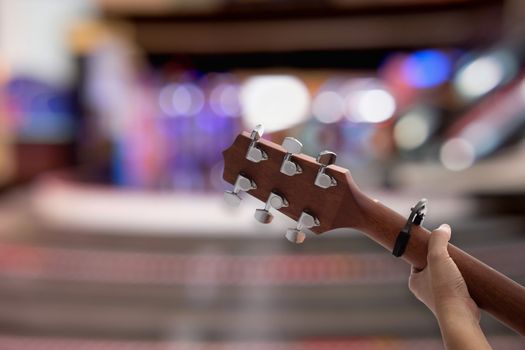 Close up woman's hands playing acoustic guitar on bokeh background.