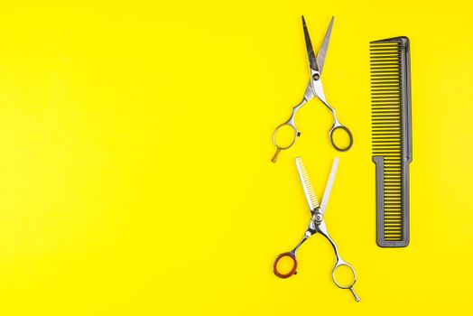 Stylish Professional Barber Scissors and comb on yellow background. Hairdresser salon concept, Hairdressing Set. Haircut accessories. Copy space image, flat lay