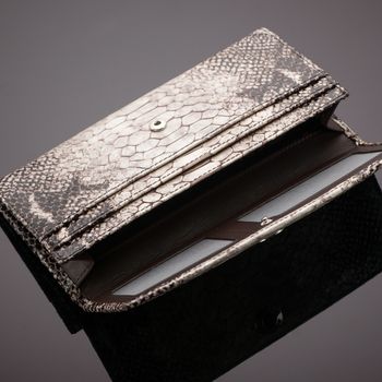 Fashionable women's wallet made of crocodile skin on a brown background