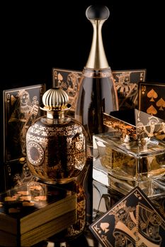 composition of luxurious women's perfume and playing cards with reflection on a black background