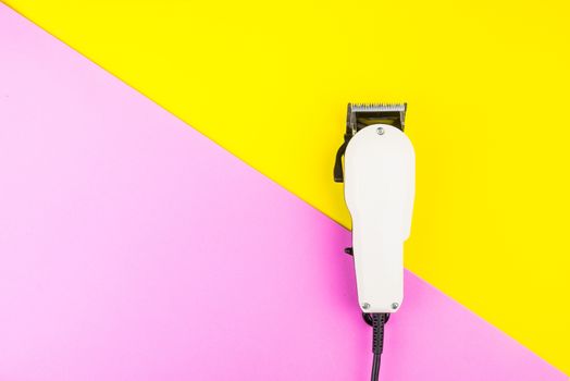 White electric clippers barber on yellow and pink background. Hairdresser salon concept, Hairdressing Set. Haircut accessories. Copy space image, flat lay