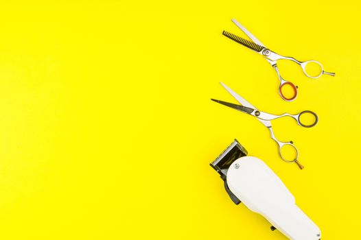 Stylish Professional Barber Scissors and White electric clippers on yellow background. Hairdresser salon concept, Hairdressing Set. Haircut accessories. Copy space image, flat lay