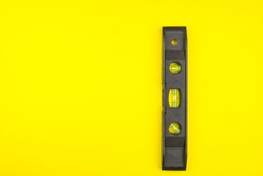 Top view of Tubular spirit level on yellow background with copy space, minimalistic style