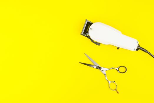 Stylish Professional Barber Scissors and White electric clippers on yellow background. Hairdresser salon concept, Hairdressing Set. Haircut accessories. Copy space image, flat lay