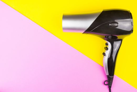 Hair dryer Professional on yellow and pink background. Hairdresser salon concept, Hairdressing Set. Haircut accessories. Copy space image, flat lay
