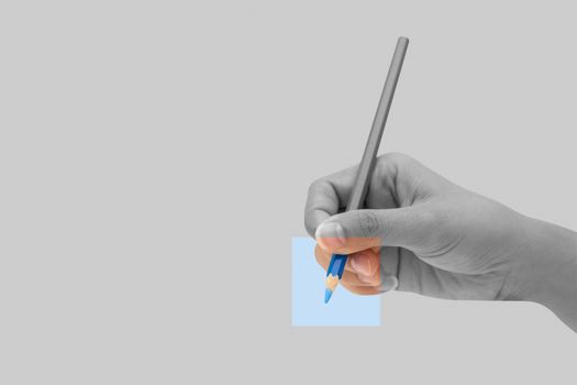 Female hand with blue color pencil isolated on grey background. Minimal idea concept.
