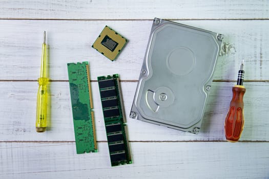 Screwdrivers, CPU chip and a hard disk  on the white wooden background