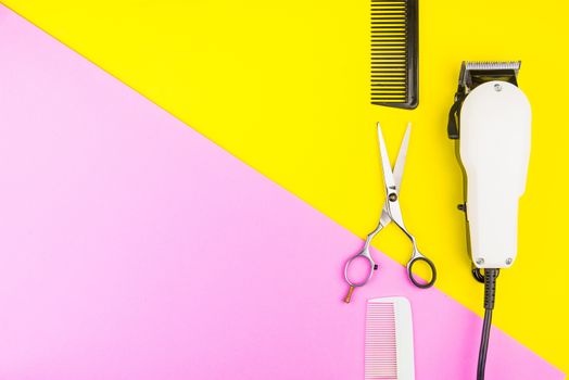 Stylish Professional Barber Scissors and White electric clippers on yellow and pink background. Hairdresser salon concept, Hairdressing Set. Haircut accessories. Copy space image, flat lay