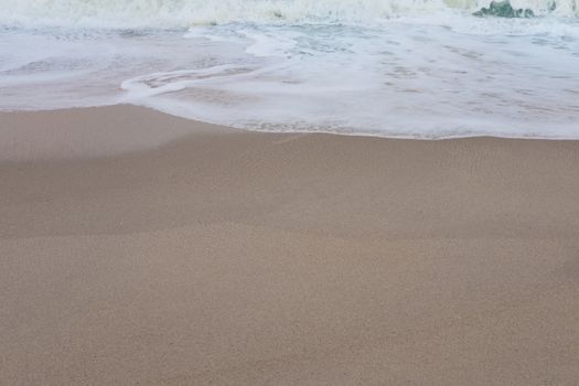 Wave of the sea and white clean foam on the sandy beach with Copy space.