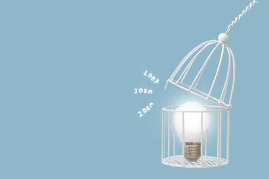 Lamp bulb in bird cage isolated on blue background, minimal idea concept.