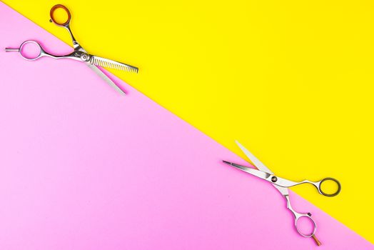 Stylish Professional Barber Scissors on yellow and pink background. Hairdresser salon concept, Hairdressing Set. Haircut accessories. Copy space image, flat lay.