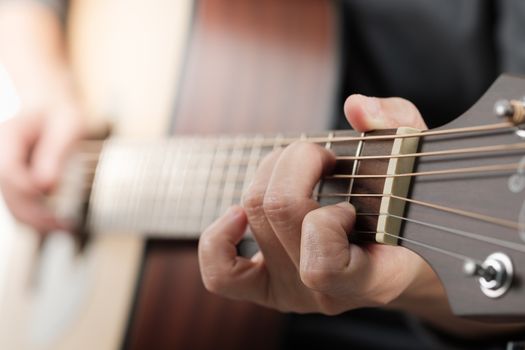 Close up woman's hands playing acoustic guitar.
