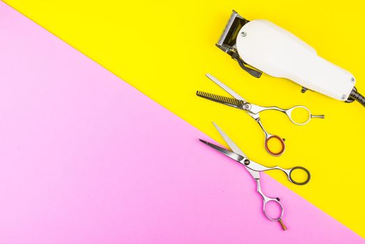Stylish Professional Barber Scissors and White electric clippers on yellow and pink background. Hairdresser salon concept, Hairdressing Set. Haircut accessories. Copy space image, flat lay