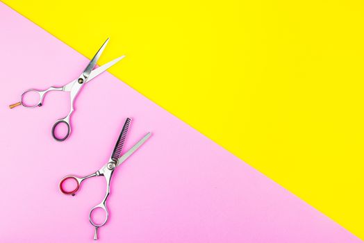 Stylish Professional Barber Scissors on yellow and pink background. Hairdresser salon concept, Hairdressing Set. Haircut accessories. Copy space image, flat lay