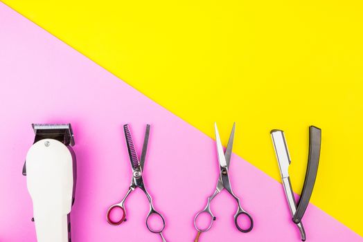 Stylish Professional Barber Scissors and White electric clippers on yellow and pink background. Hairdresser salon concept, Hairdressing Set. Haircut accessories. Copy space image, flat lay