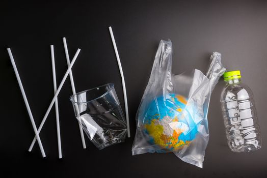 Earth world globe and plastic bottle waste on the black background.Saving the planet Earth from plastic bags concept.Global warming.Plastic waste overflows the world