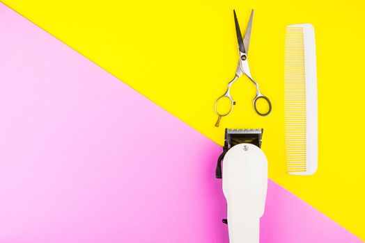 Stylish Professional Barber Scissors and White electric clippers on yellow and pink background. Hairdresser salon concept, Hairdressing Set. Haircut accessories. Copy space image, flat lay