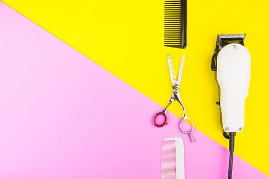 Stylish Professional Barber Scissors and White electric clippers on yellow and pink background. Hairdresser salon concept, Hairdressing Set. Haircut accessories. Copy space image, flat lay