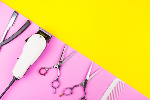 Stylish Professional Barber Scissors and White electric clippers on yellow and pink background. Hairdresser salon concept, Hairdressing Set. Haircut accessories. Copy space image, flat lay