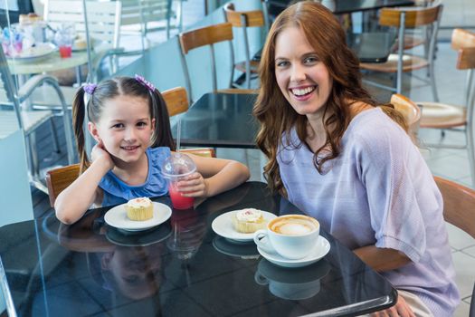 Mother and daughter enjoying cakes in coffee shop