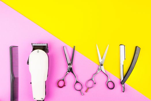 Stylish Professional Barber Scissors and White electric clippers on yellow and pink background. Hairdresser salon concept, Hairdressing Set. Haircut accessories. Copy space image, flat lay