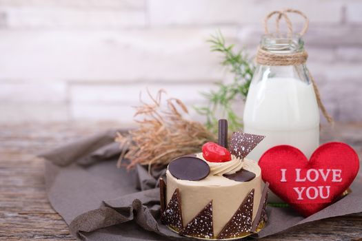 Cake and a bottle of milk on a  wooden table in warm light, Vintage tone, Space to write, Valentine concept.