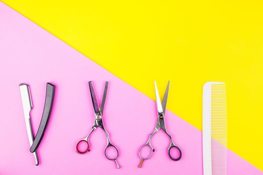 Stylish Professional Barber Scissors and comb on yellow and pink background. Hairdresser salon concept, Hairdressing Set. Haircut accessories. Copy space image, flat lay