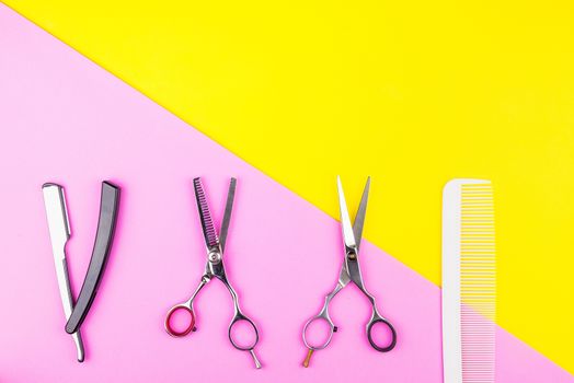 Stylish Professional Barber Scissors and comb on yellow and pink background. Hairdresser salon concept, Hairdressing Set. Haircut accessories. Copy space image, flat lay