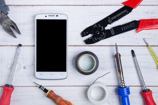 smartphone and equipment repair on the white wooden background.