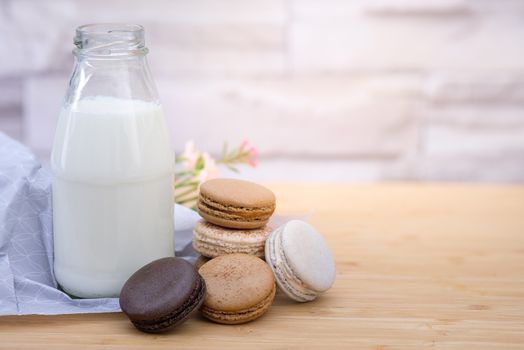 Chocolate, coffee macaroons and a bottle of milk on a  wooden table in warm light, Vintage tone, Space to write.