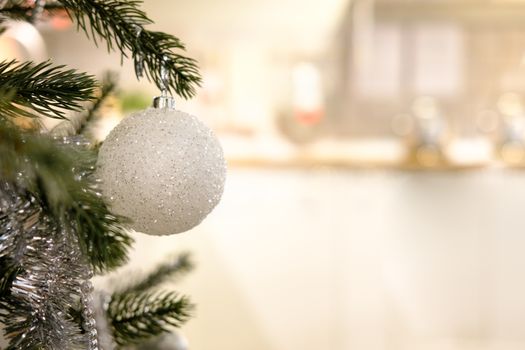 Closeup of a white Glitter Ball hanging from a decorated Christmas tree. Retro filter effect, AF point selection.