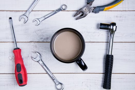 Coffee cup and equipment repair on the white wooden background.