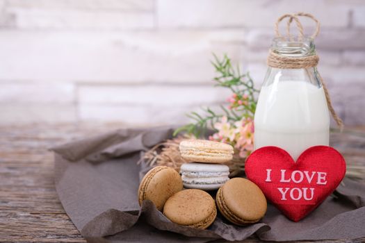 Chocolate, coffee macaroons and a bottle of milk on a  wooden table in warm light, Vintage tone, Space to write, Valentine concept.