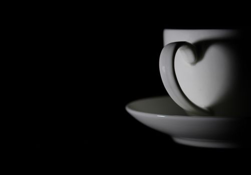 Hot coffee in white ceramic cup with shiny heart shadow, with copy space to write. Valentine concept.