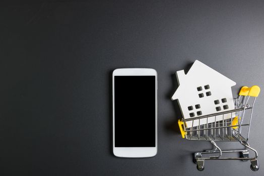 Shopping cart, Wooden hose model and smartphone.Online shopping concept.Real estate concept, New house concept.Buying a house.