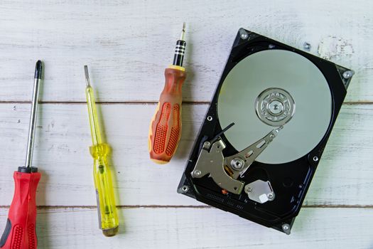 Screwdrivers and a hard disk  on the white wooden background.