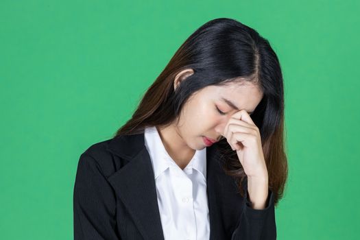 Frustrated stressed young Asian business woman with hands on face in depression on green isolated background.