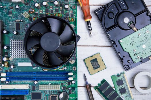 Computer motherboard, Computer Parts, Hard disk, Ram and equipment repair on the white wooden background.