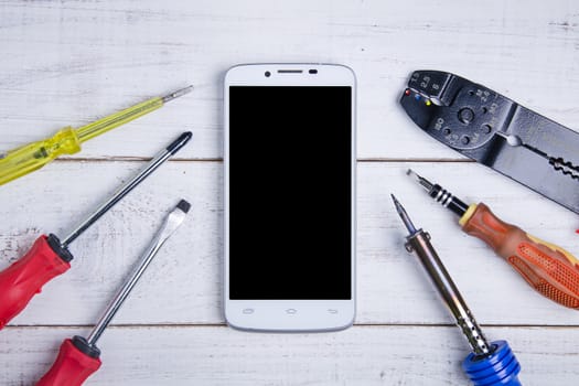 smartphone and equipment repair on the white wooden background