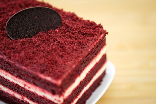 Red velvet cake and white cream on wooden table, close up, space to write.