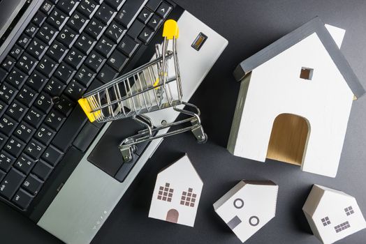 Shopping cart and  paper hose model on laptop notebook.Online shopping concept.Real estate concept, New house concept.Buying a house.