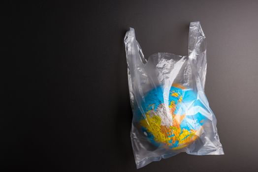 Plastic bag Earth world globe isolated on black background. Saving the planet Earth from plastic bags concept