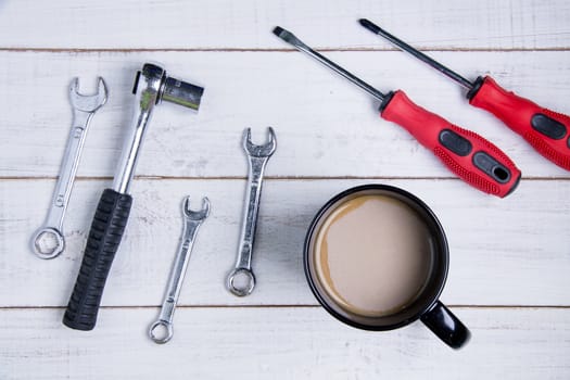 Coffee cup and equipment repair on the white wooden background.